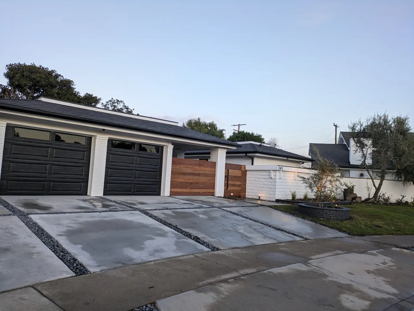 Modern concrete driveway with dark stone joints and landscape lighting